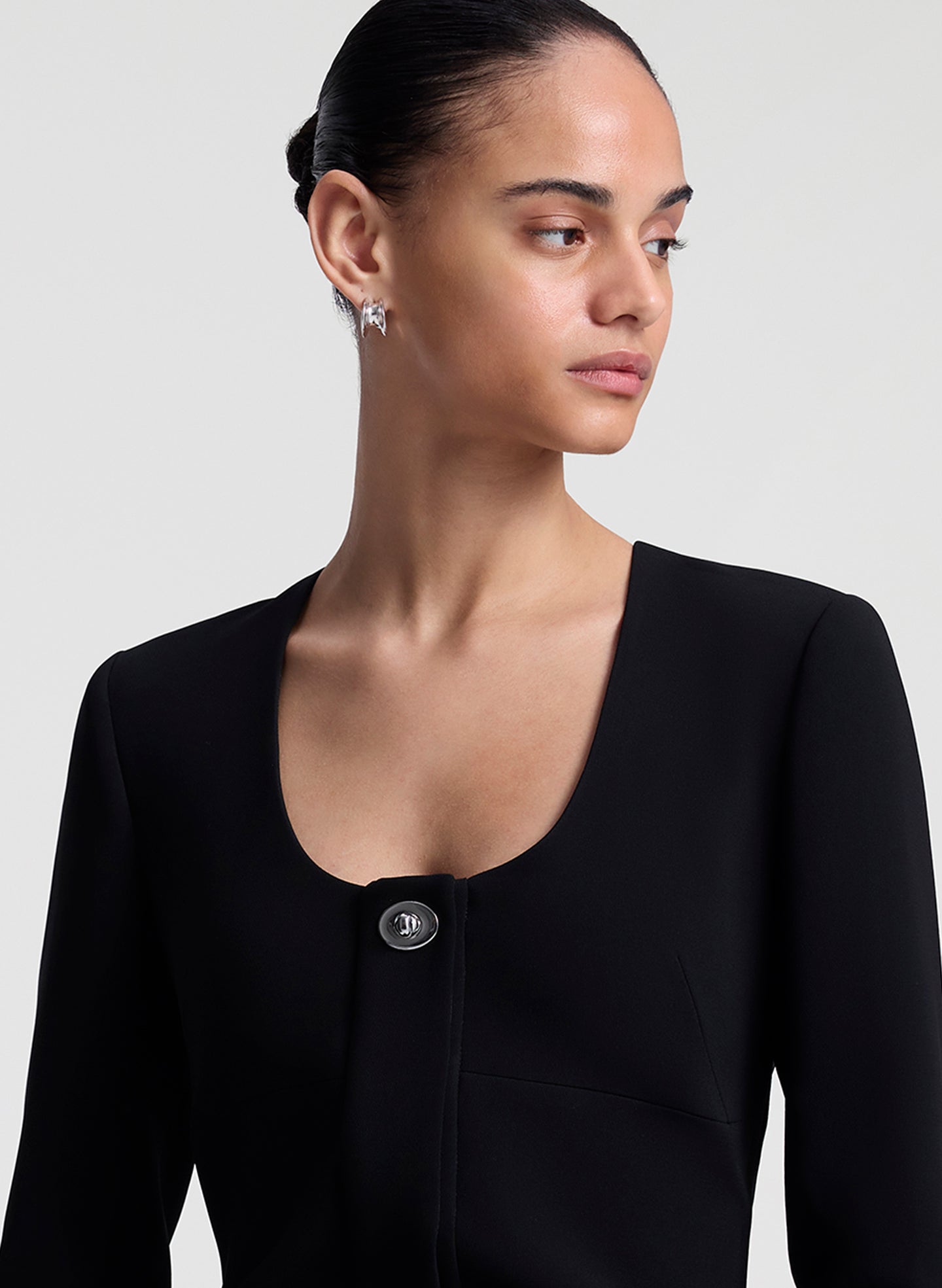 Woman wearing a black mini dress against a plain background