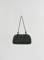 A small green woven leather shoulder bag with a single thin strap, photographed against a plain light gray background.