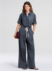 woman wearing blue striped top and pants carrying burgundy clutch bag