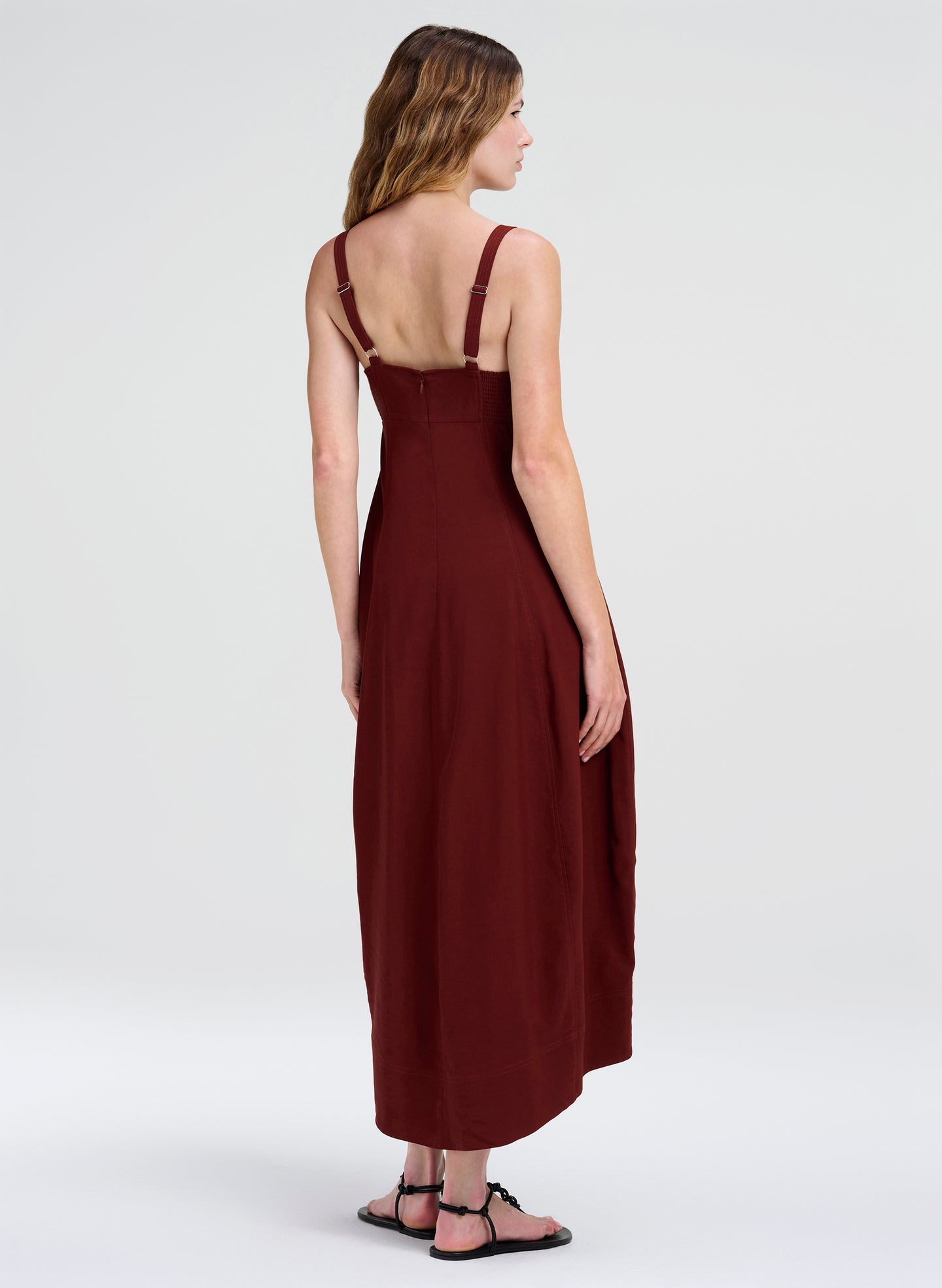 Woman wearing a burgundy dress with thin straps on a white background