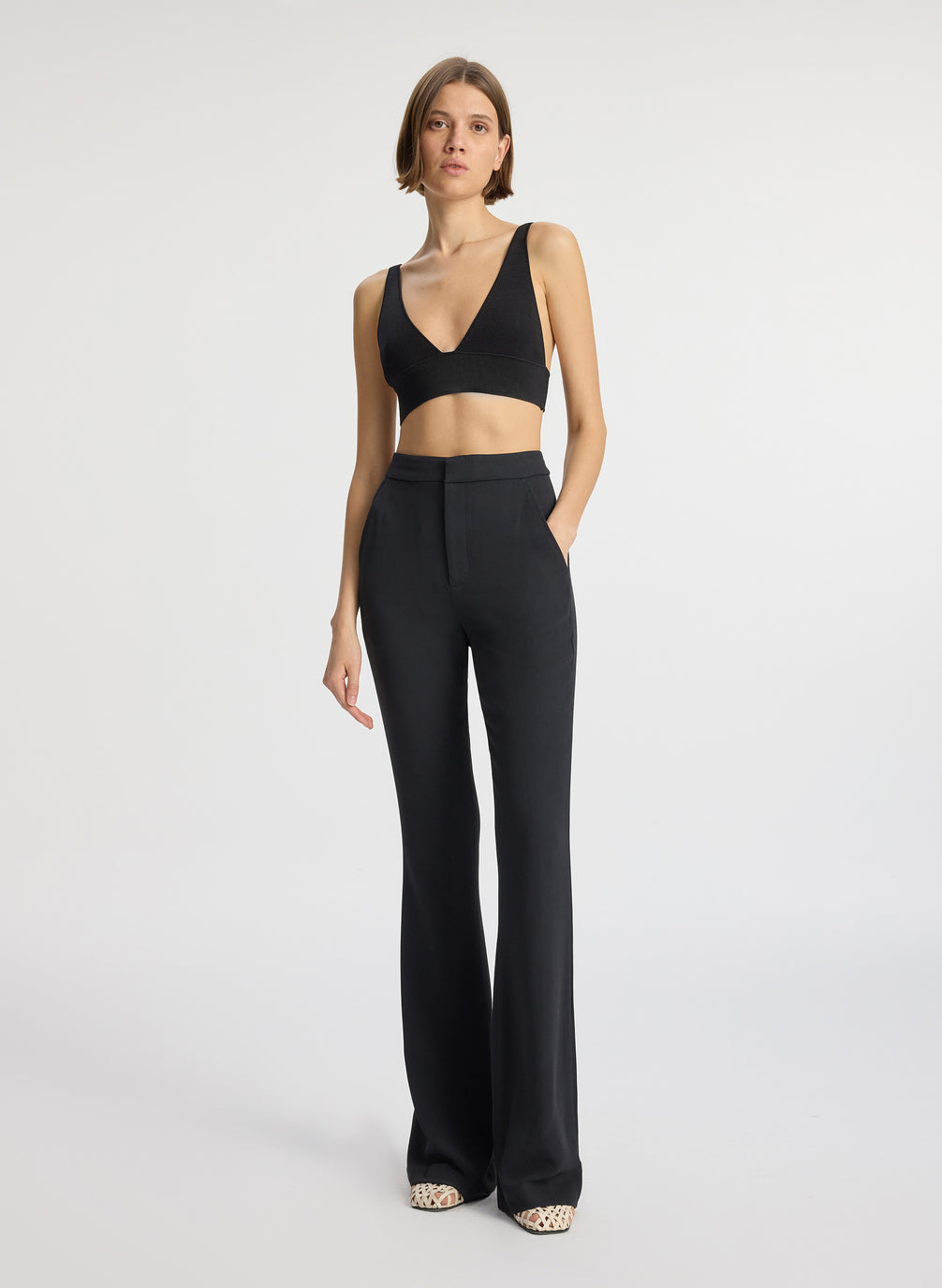 front view of woman wearing black knit bra and black flared pants