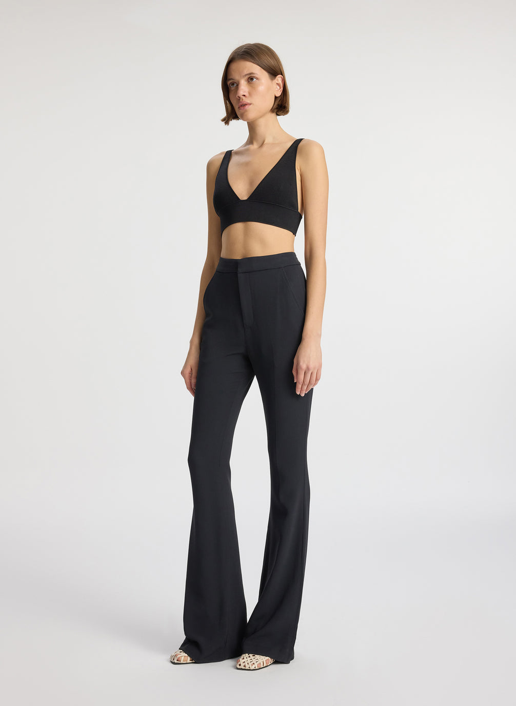side view of woman wearing black knit bra and black flared pants