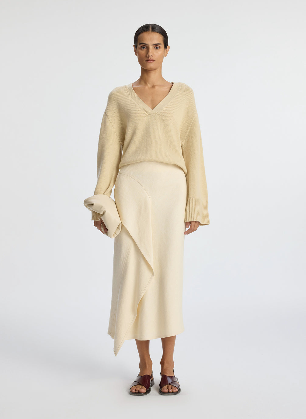 front view of woman wearing beige v neck sweater and cream skirt