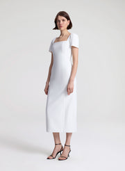 Woman wearing a white midi dress on a plain background