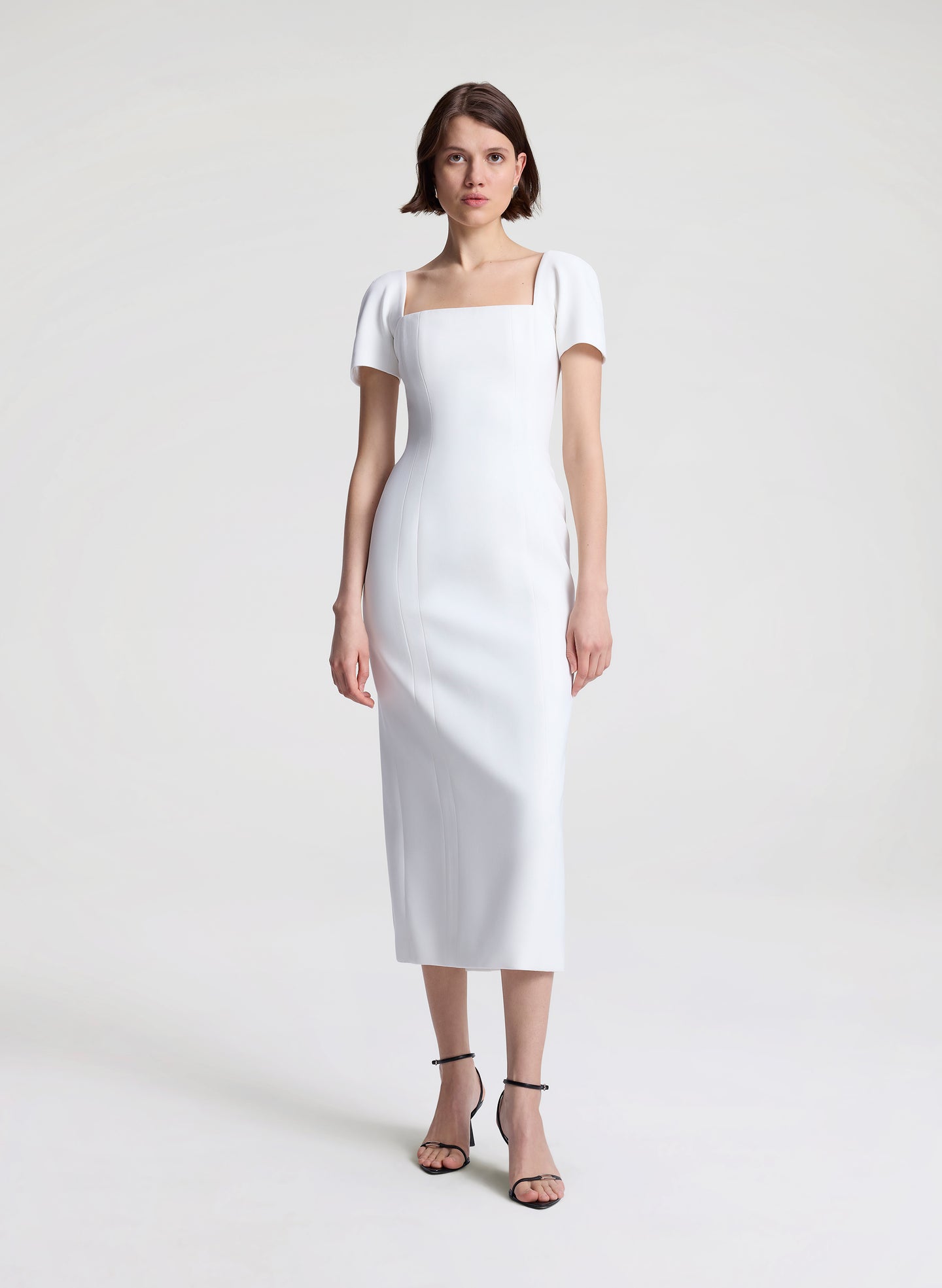 Woman wearing a white midi dress on a plain background