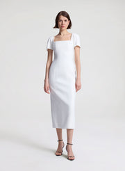 Woman wearing a white midi dress on a plain background