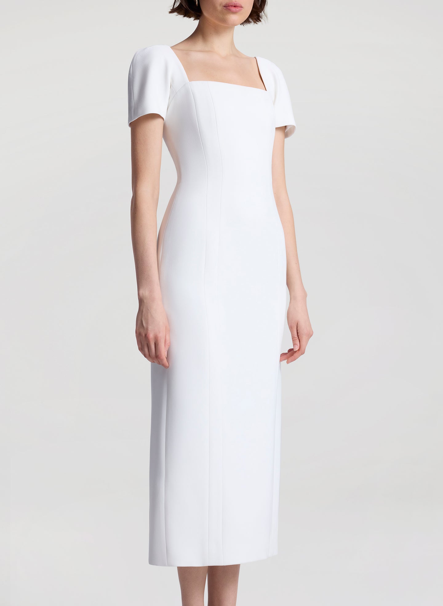 Woman wearing a white midi dress on a plain background