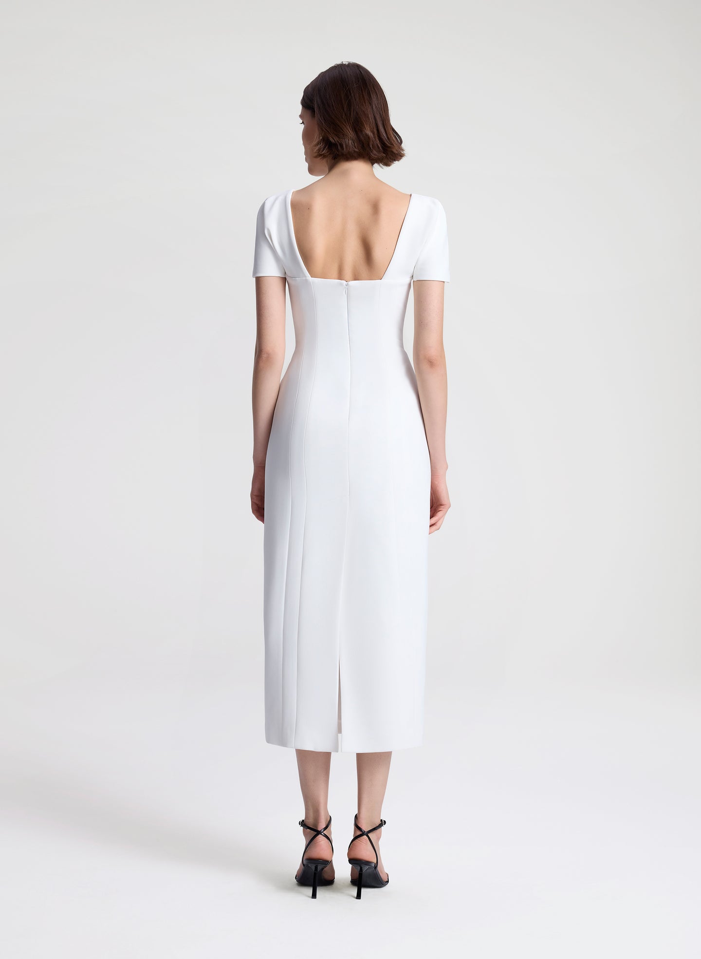 Woman wearing a white midi dress on a plain background