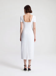Woman wearing a white midi dress on a plain background