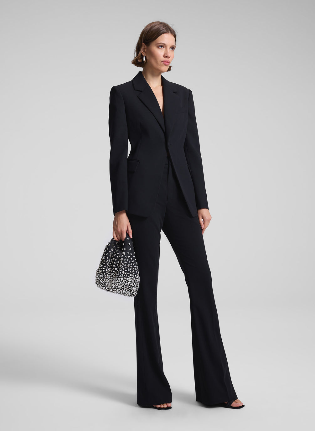 woman in black suit with black rhinestone embellished handbag