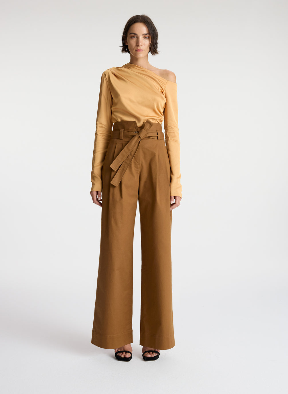 front view of woman wearing tan one shoulder long sleeve top and brown wide leg pants