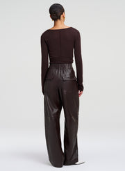 A model shown from the back wearing a dark brown long-sleeve top and matching dark brown leather wide-leg pants, set against a plain light gray studio background.
