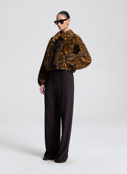 Person wearing a leopard print jacket and black pants on a white background