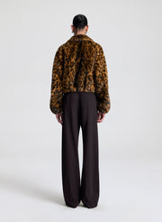 Person wearing a leopard print jacket and black pants on a white background
