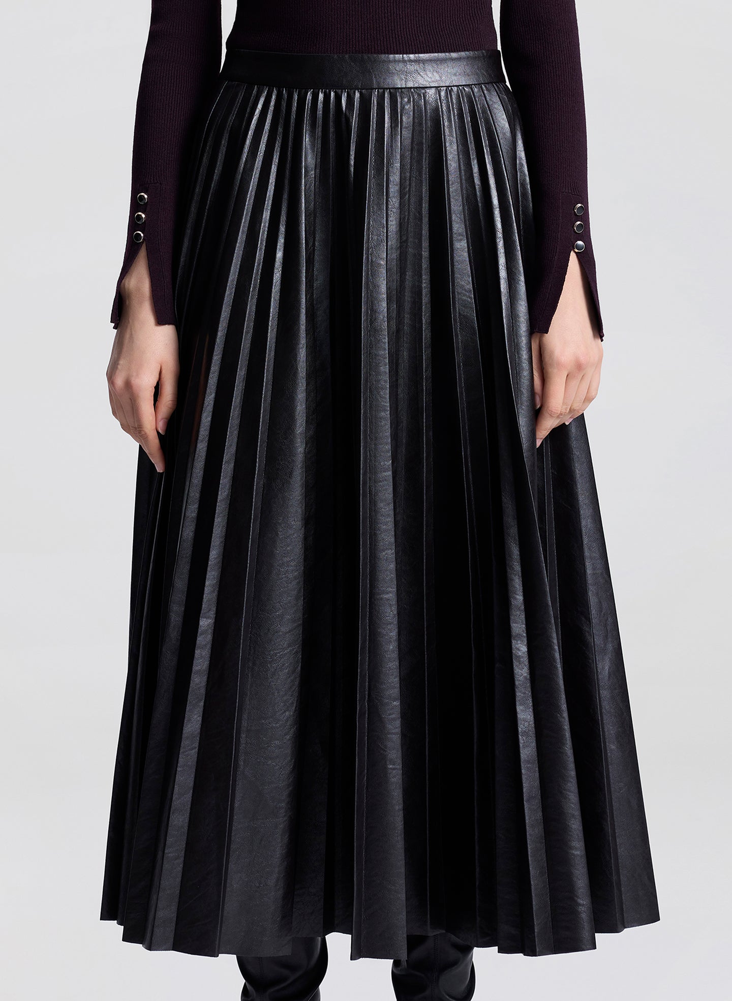 Black pleated skirt worn by a person on a white background