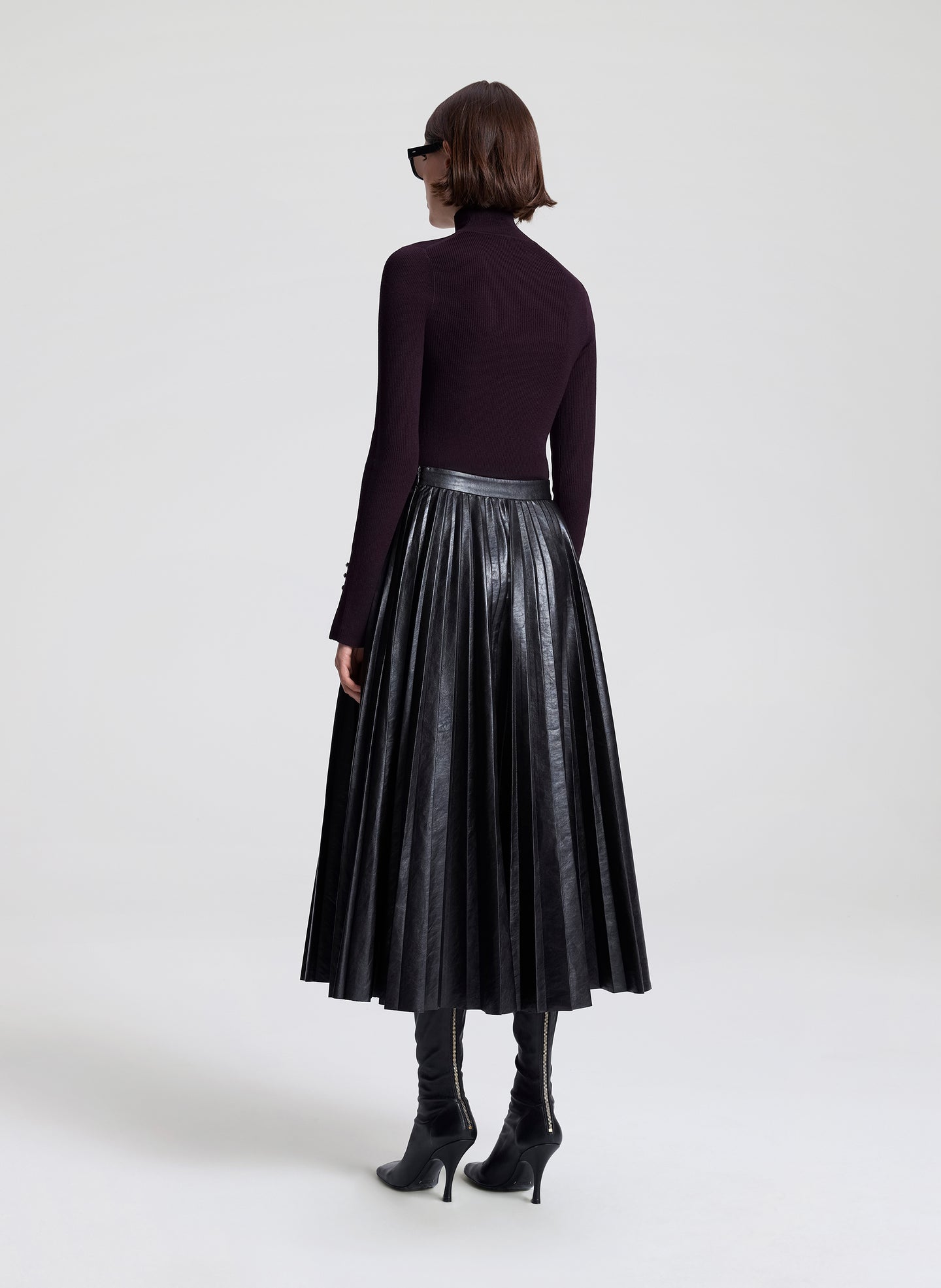 Person wearing a black leather skirt on a white background