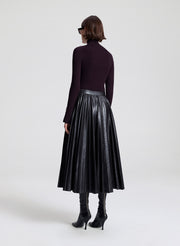 Person wearing a black leather skirt on a white background