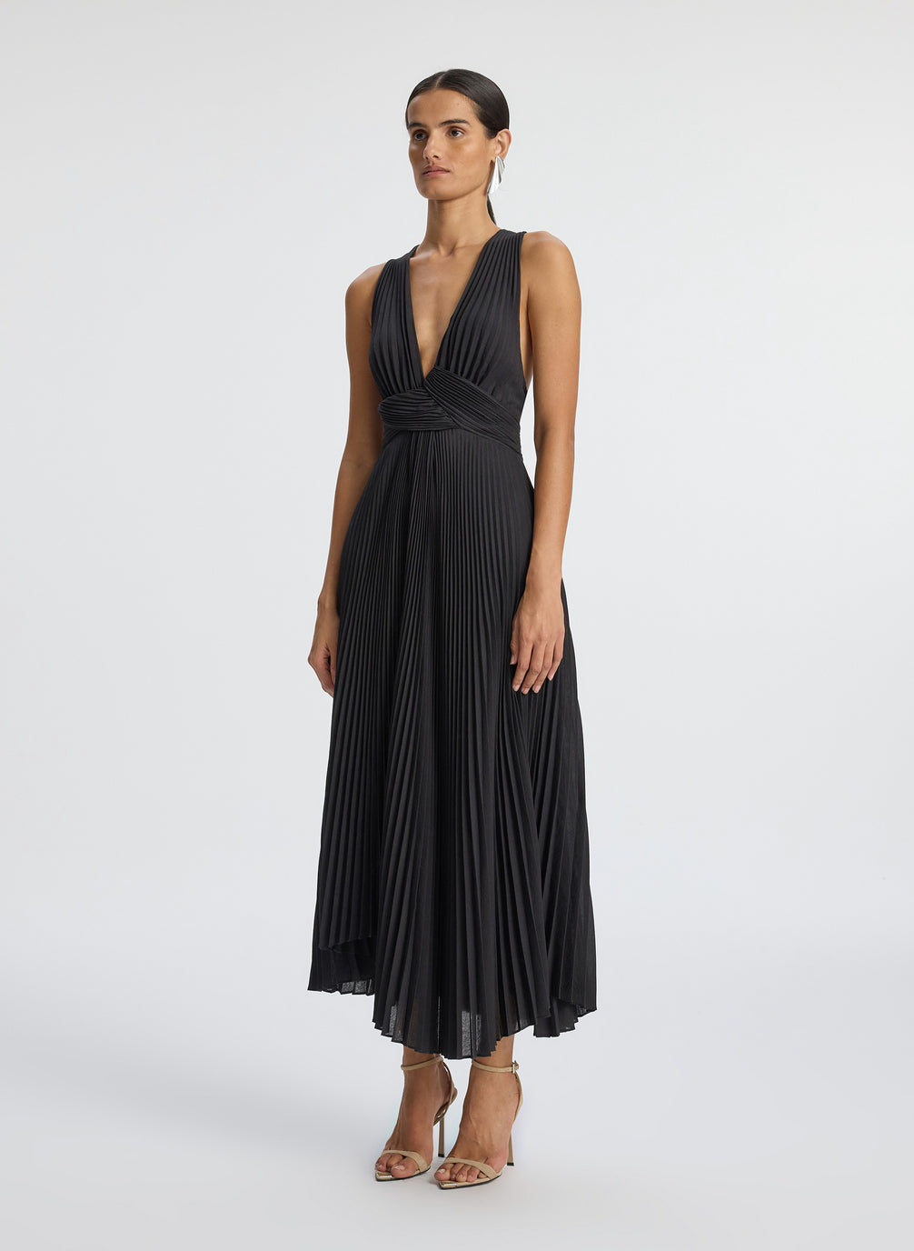 side view of woman wearing black deep v-neck pleated midi dress
