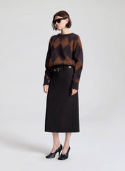 Person wearing a brown and black checkered sweater with a black skirt on a white background