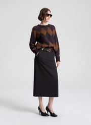 Woman wearing a patterned sweater and black skirt on a white background