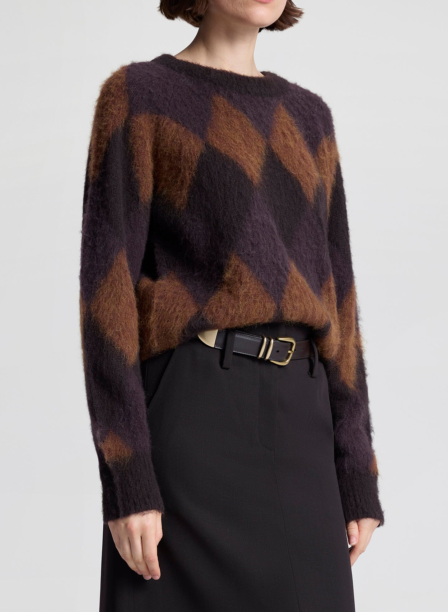 Person wearing a patterned sweater and black skirt on a plain background