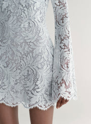 Woman wearing a light blue lace dress on a white background