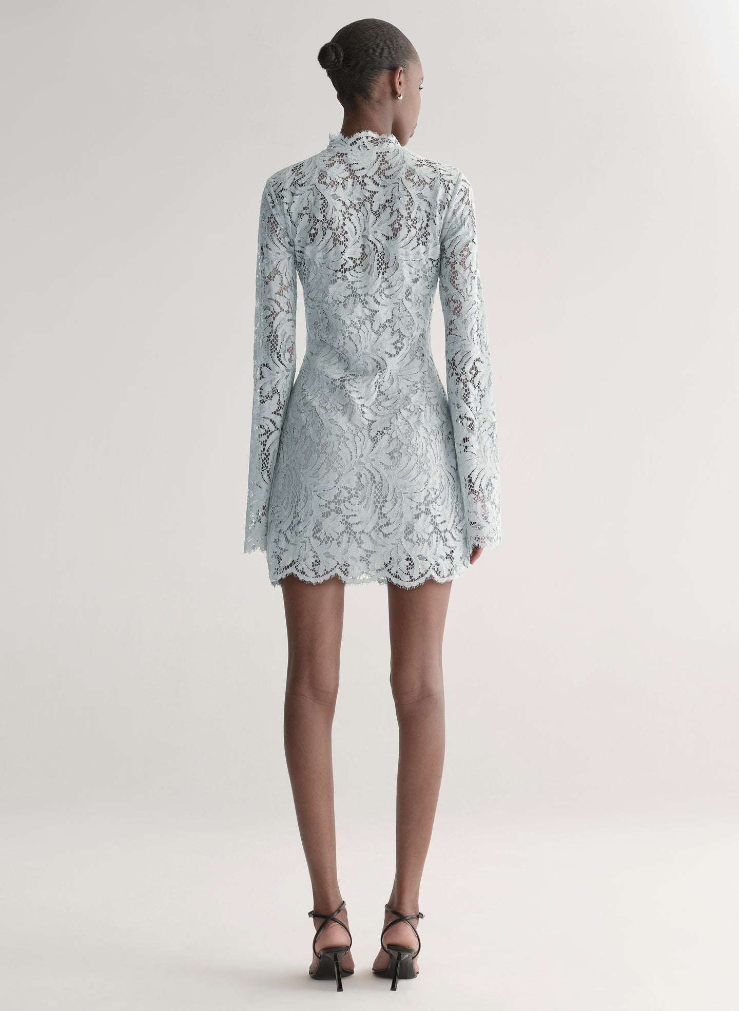 Woman wearing a light blue lace dress on a white background