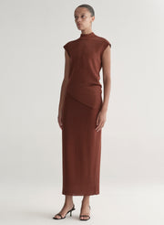 Woman wearing a rust colored sleeveless top and skirt set against a plain background