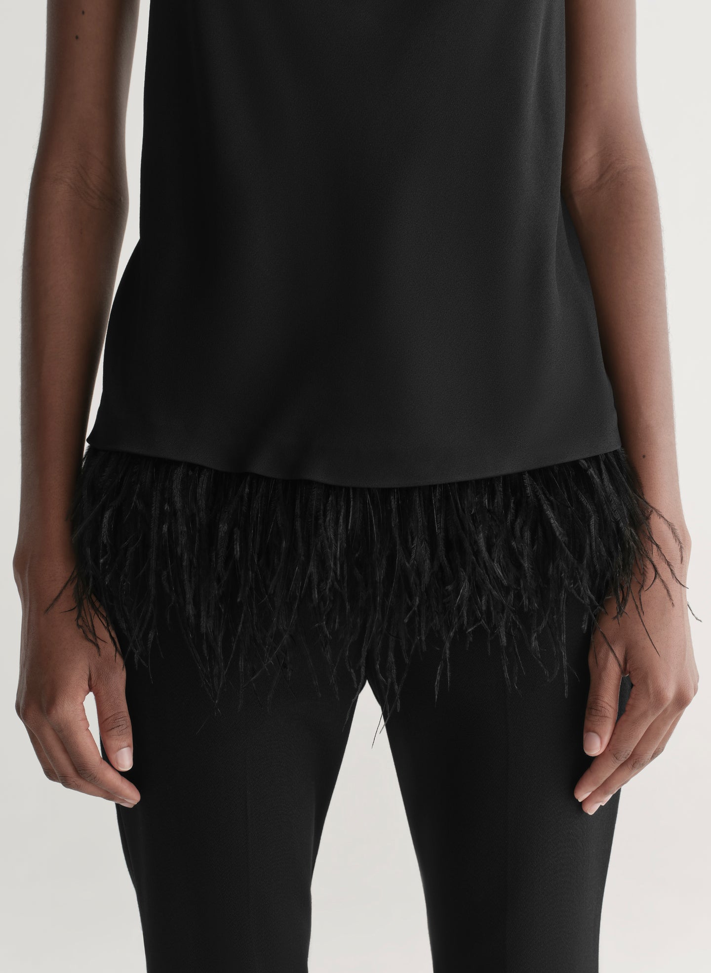woman wearing black feather trim camisole and black pants
