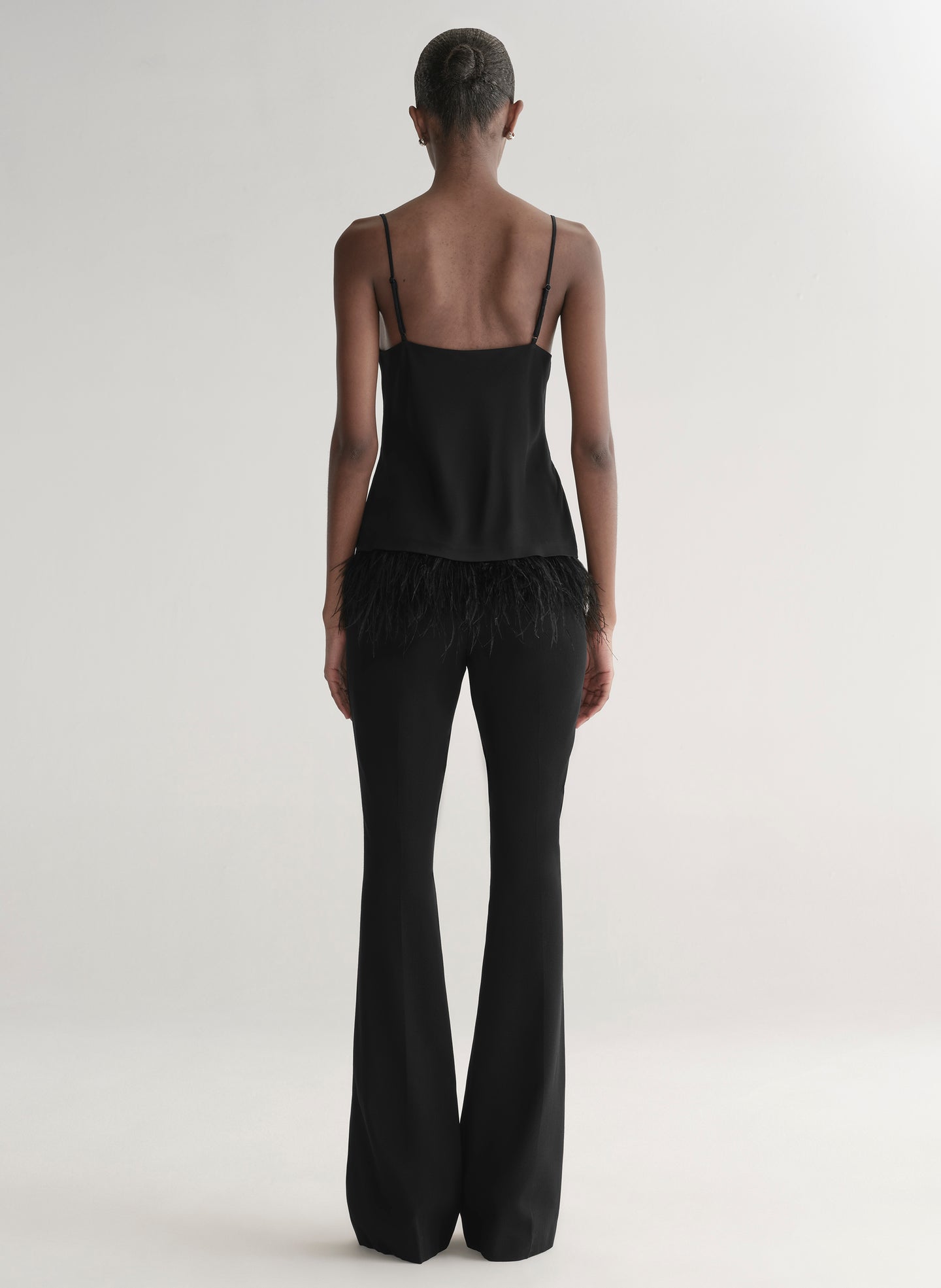 woman wearing black feather trim camisole and black pants
