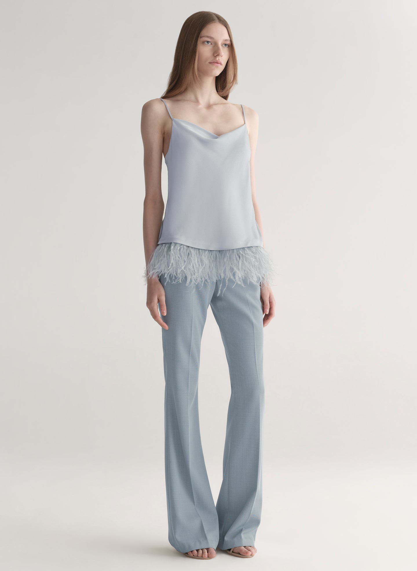 woman wearing light blue feather trim camisole and light blue pants