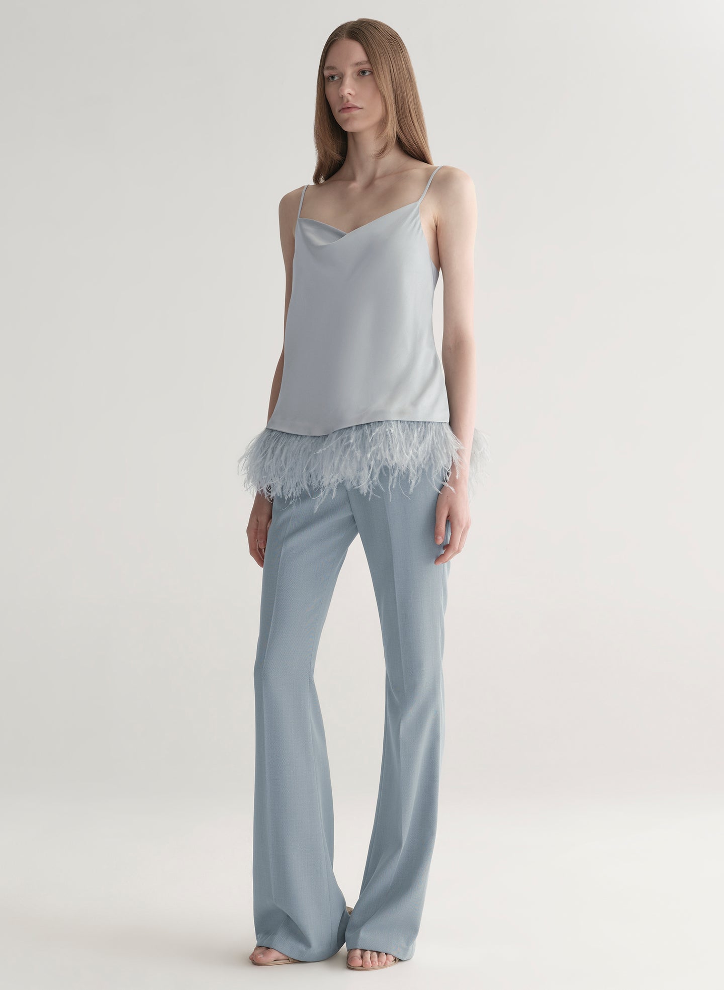 woman wearing light blue feather trim camisole and light blue pants