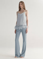 woman wearing light blue feather trim camisole and light blue pants