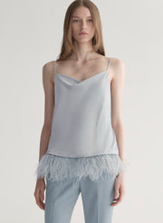 woman wearing light blue feather trim camisole and light blue pants