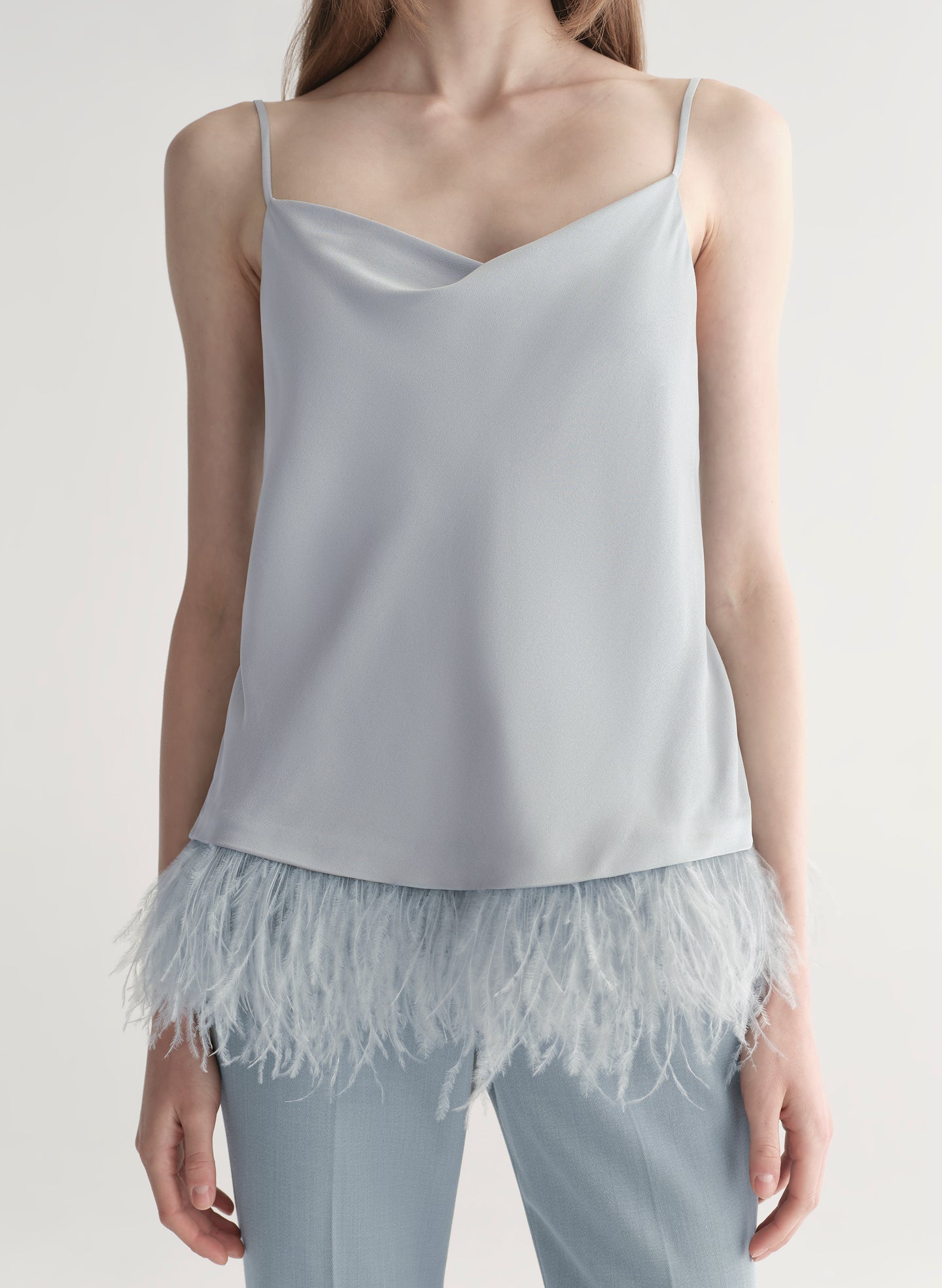 woman wearing light blue feather trim camisole and light blue pants