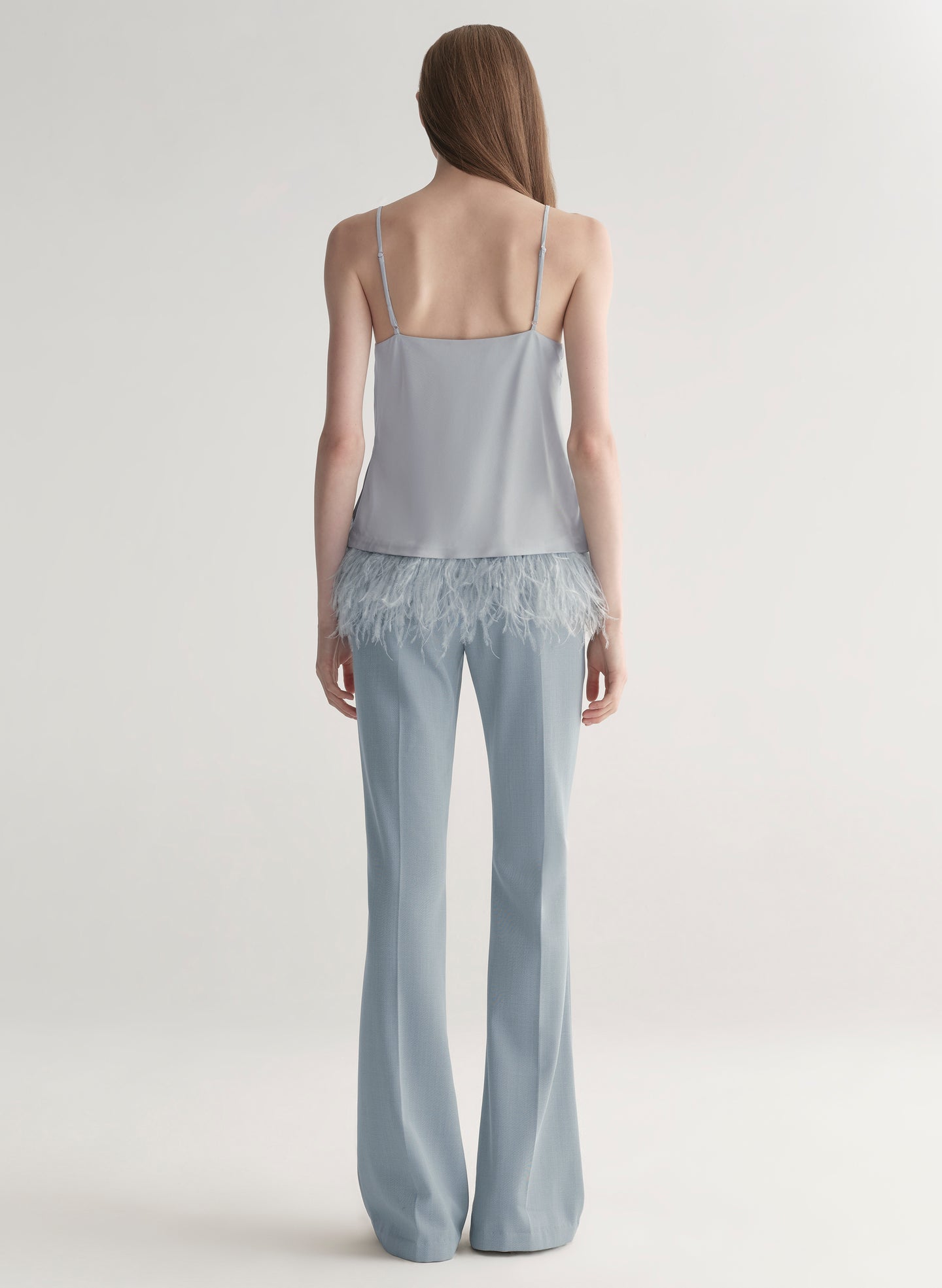 woman wearing light blue feather trim camisole and light blue pants