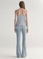 woman wearing light blue feather trim camisole and light blue pants