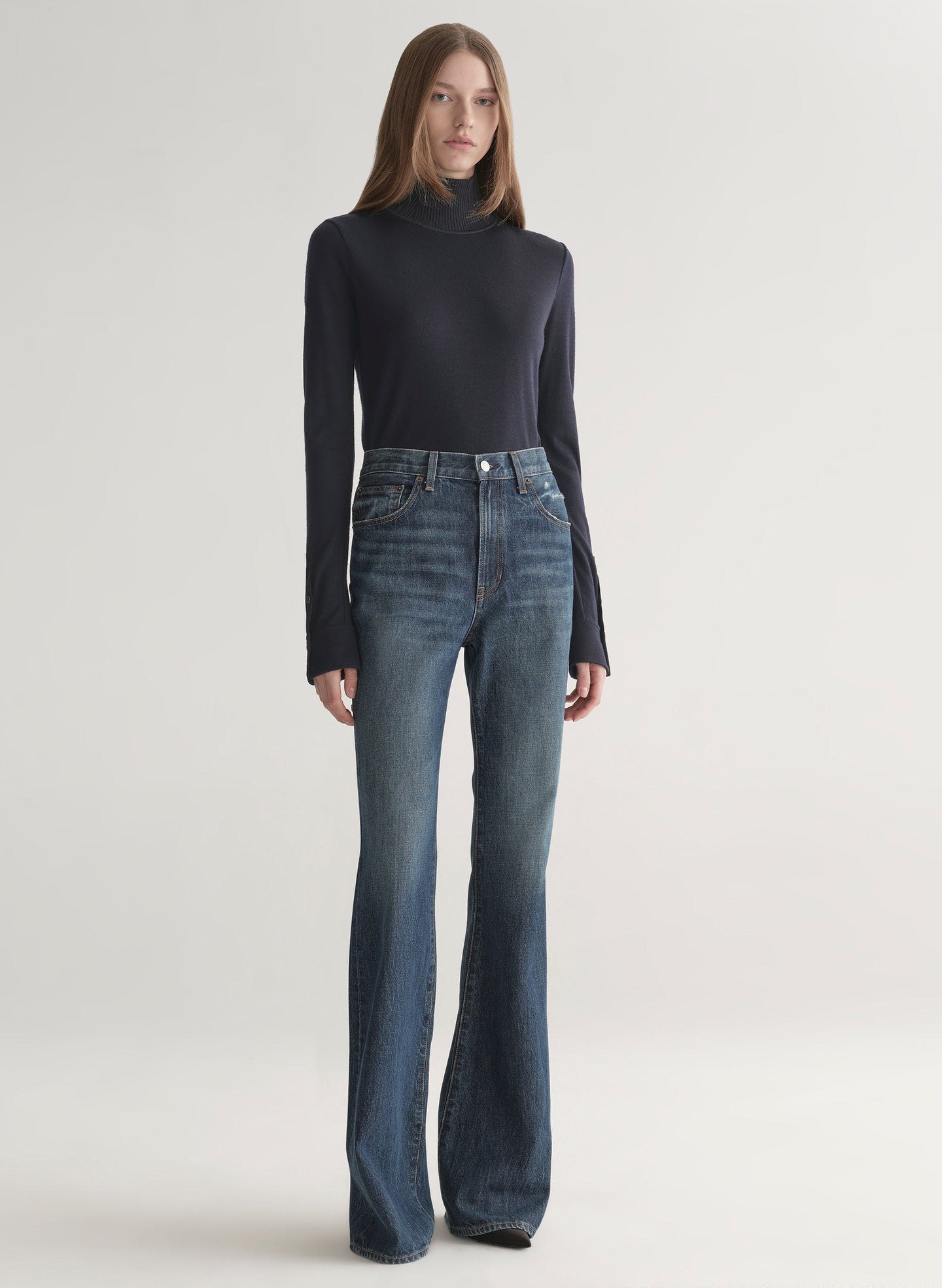 woman wearing dark blue turtleneck and blue denim jeans