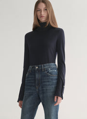 woman wearing dark blue turtleneck and blue denim jeans