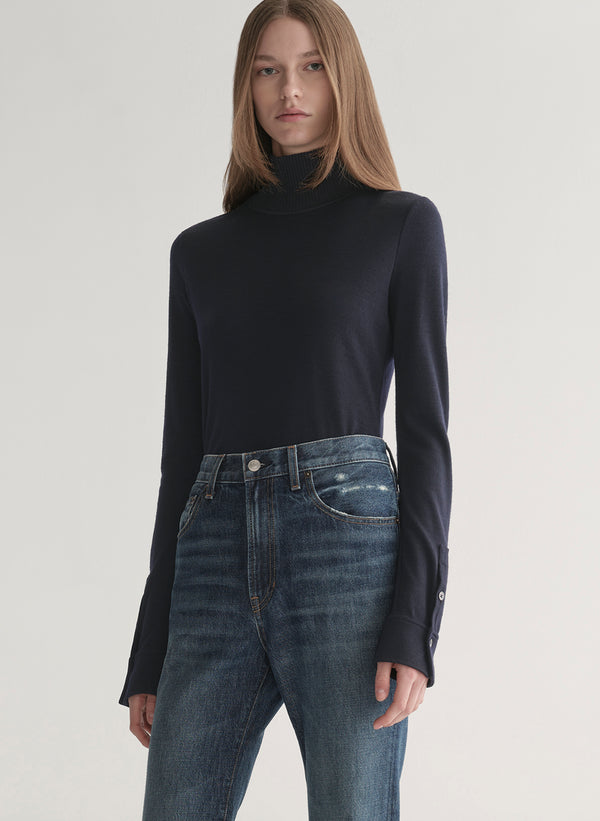 woman wearing dark blue turtleneck and blue denim jeans