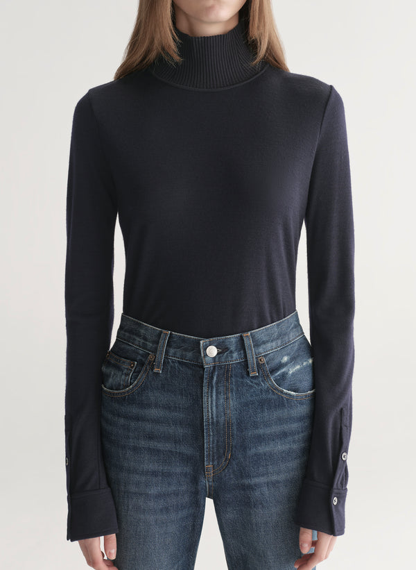 woman wearing dark blue turtleneck and blue denim jeans