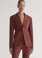 Woman wearing a maroon suit against a plain background