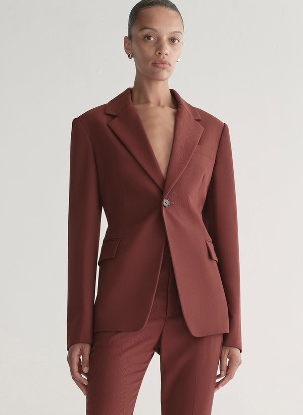 Woman wearing a maroon suit against a plain background