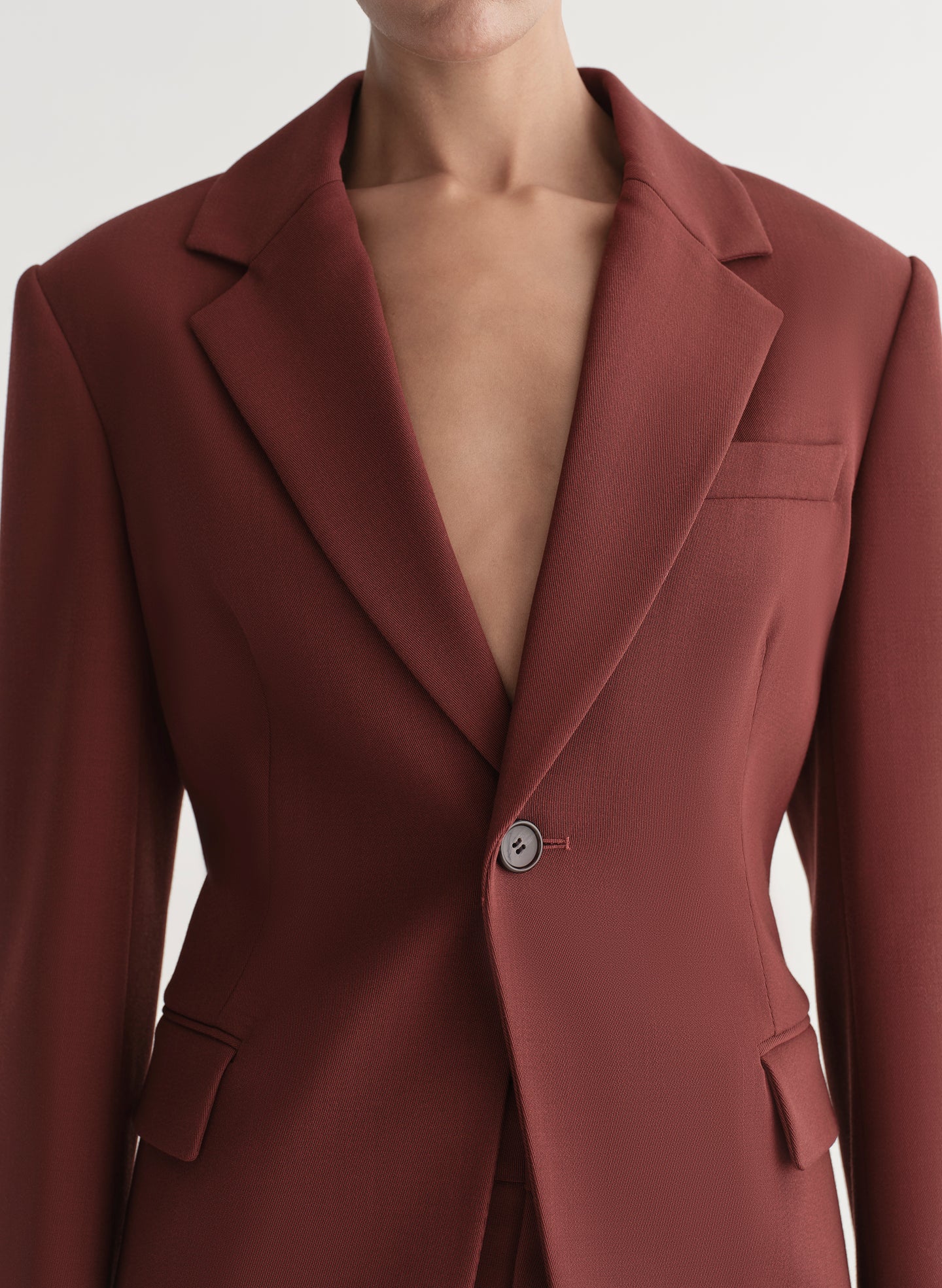 Woman wearing a maroon suit against a plain background
