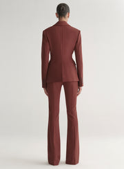 Woman wearing a maroon suit against a plain background