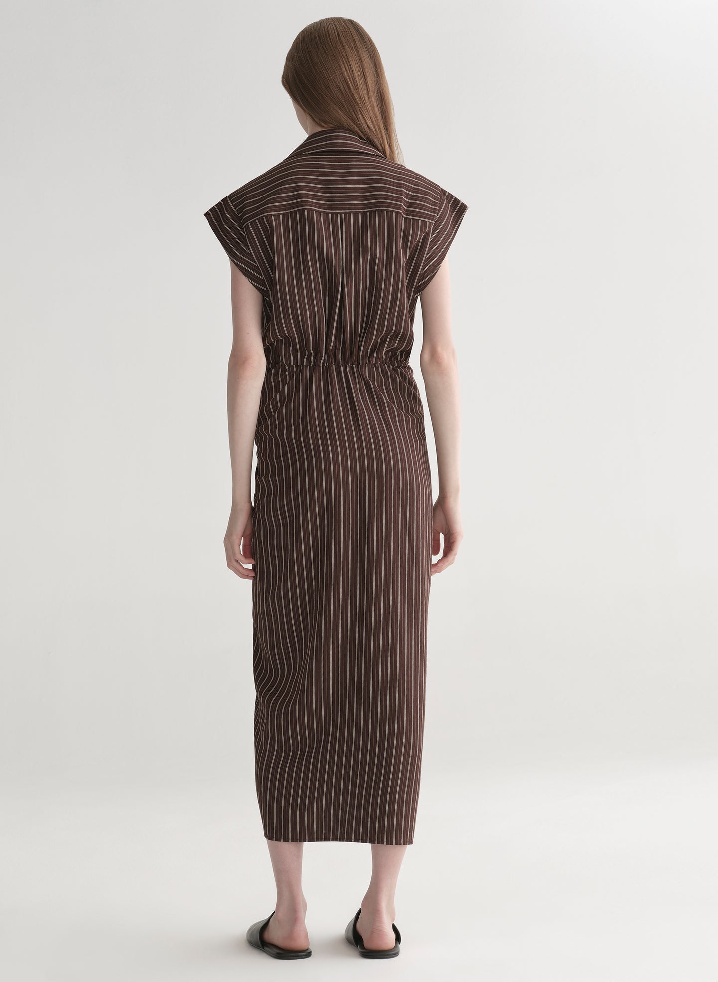 Woman wearing a brown striped dress on a white background