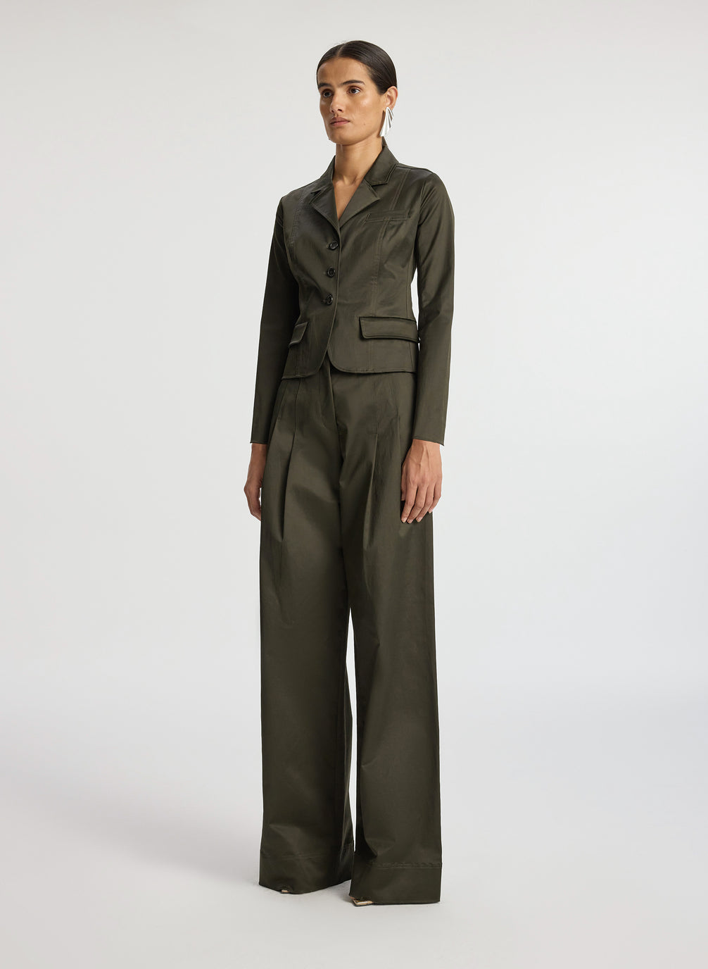 side view of woman in olive green sateen suit jacket and wide leg pants