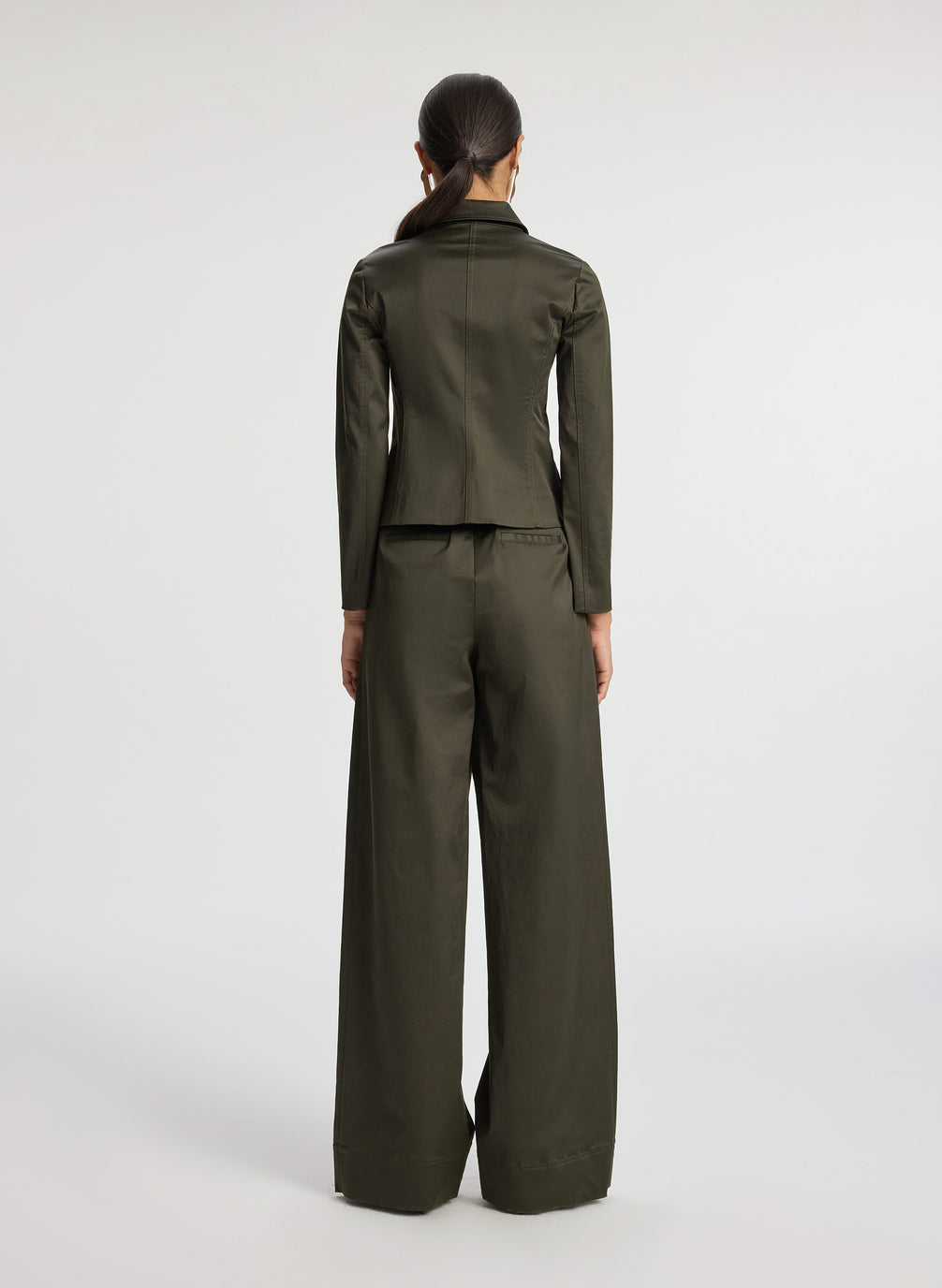 back view of woman in olive green sateen suit jacket and wide leg pants