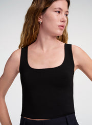 Woman wearing a black tank top against a white background