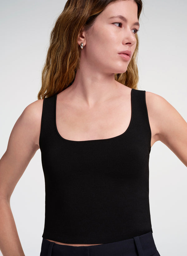 Woman wearing a black tank top against a white background